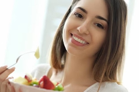 A woman with a beautiful smile eating fruits.