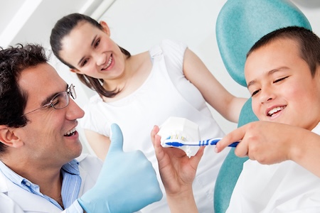 A happy dental hygienist with his adorable little patient at the dental office.