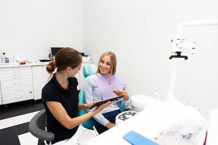 A female dental hygienist consulting with her patient at her dental office.