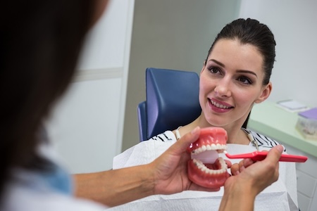 A dentist showing her patient how an impacted tooth can cause misalignment.