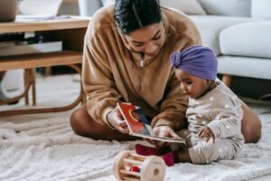Mother reading to baby on floor carpet