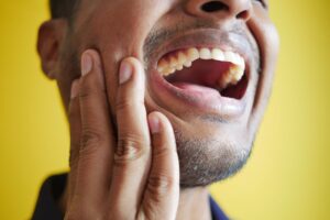 Man experiencing toothache holding cheek