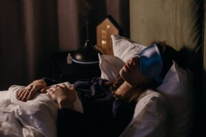 Person sleeping with sleep mask on bed
